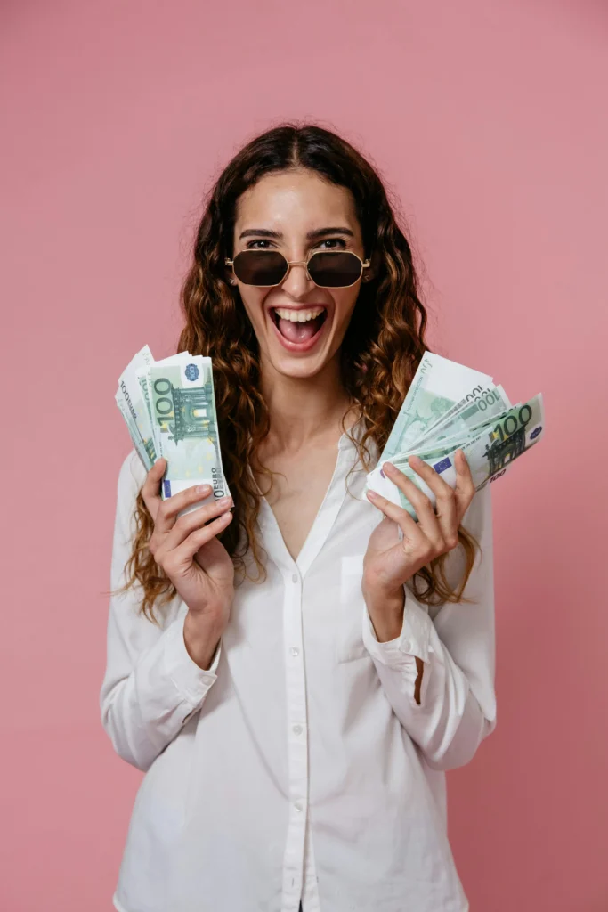 Mujer feliz con billetes de euro representando el complemento de apoyo al empleo en 2025.